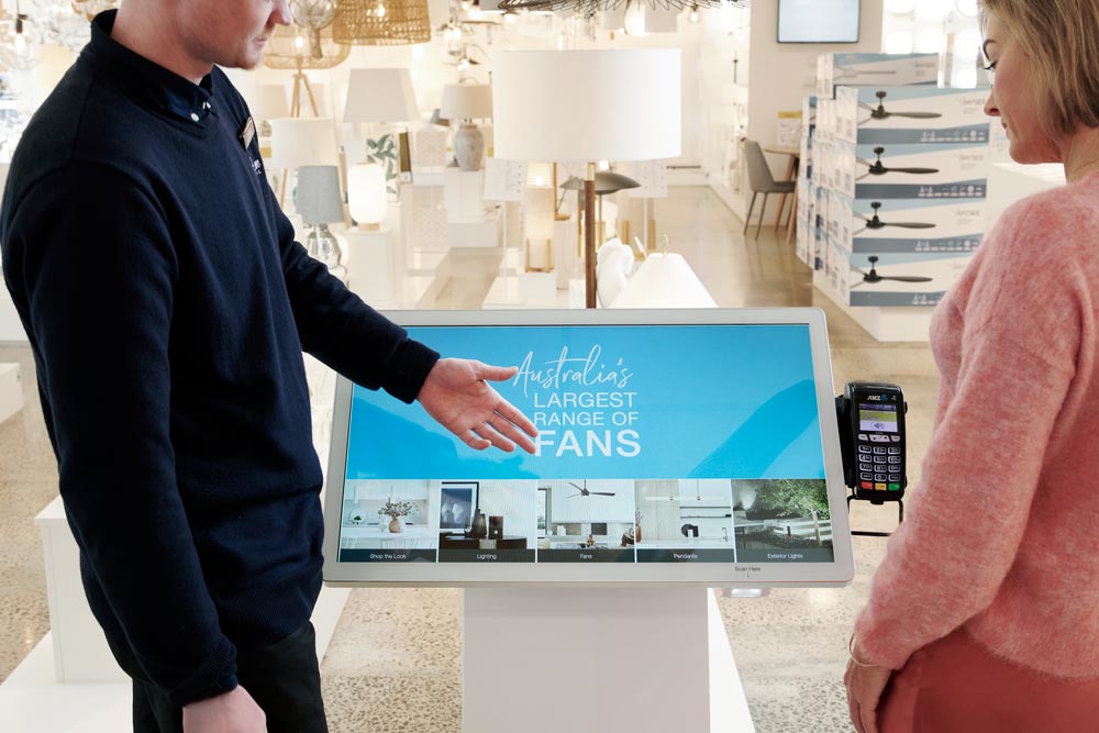 Store manager helps a customer navigate the touchscreen system at this store